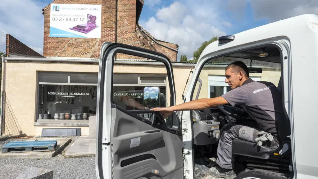 Chauffeur de marbrerie funéraire au volant de son camion de livraison.